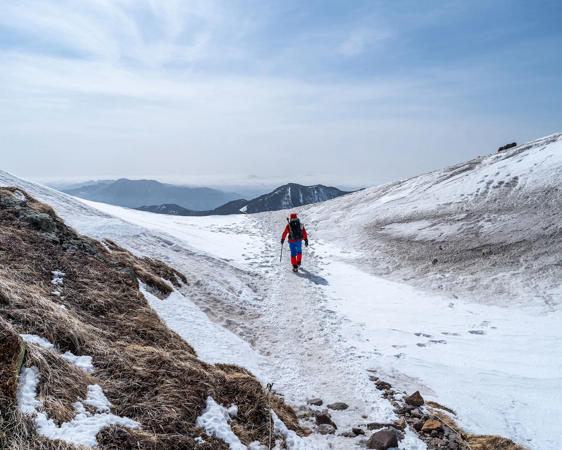 日光白根山の急な雪の斜面をアイゼンを効かせて登るハイカー。頂上へと続く真っ白なビクトリーロード。