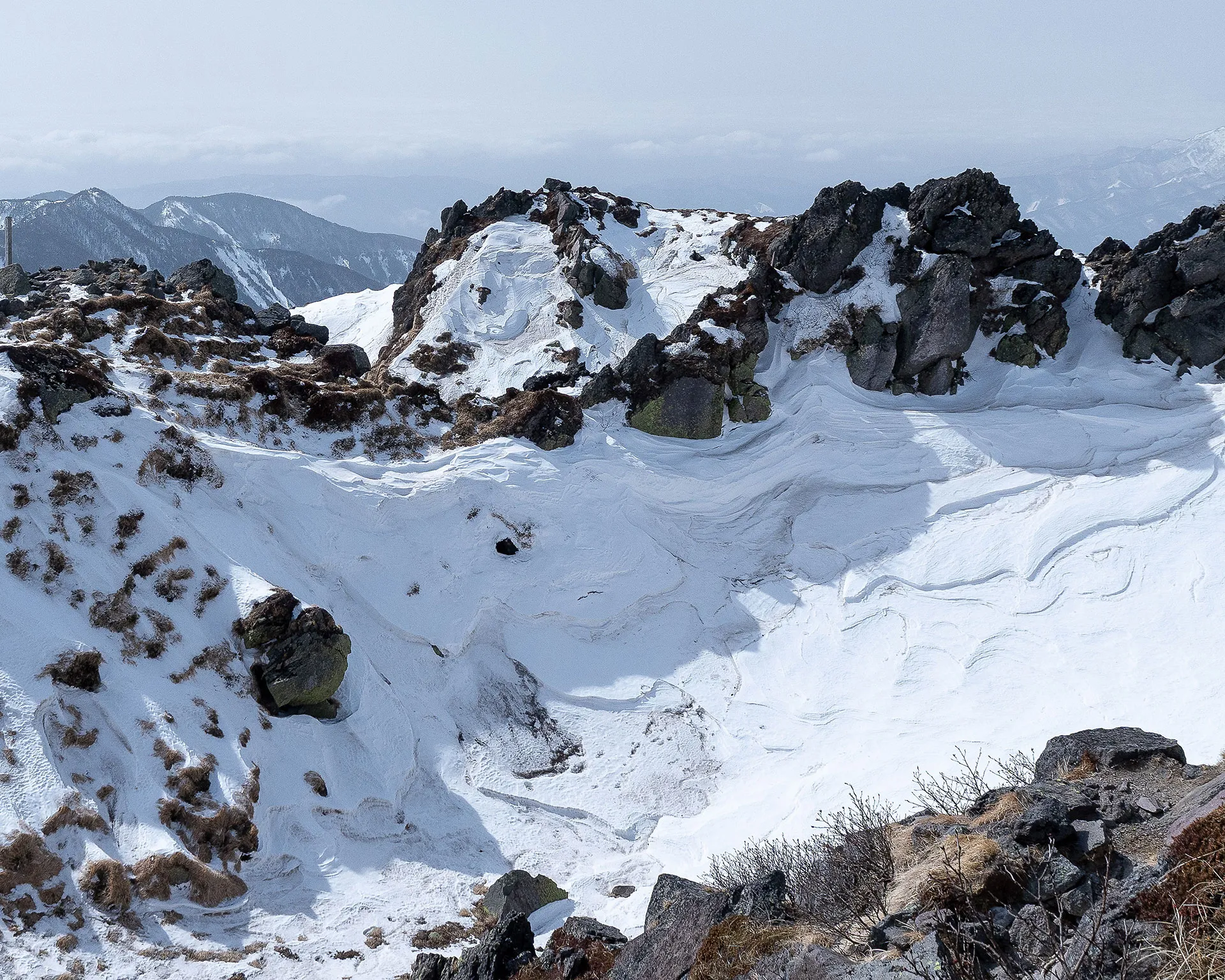 複雑な岩肌と真っ白な雪が混ざり合う日光白根山頂付近の火口壁。荒々しい火山らしい地形。