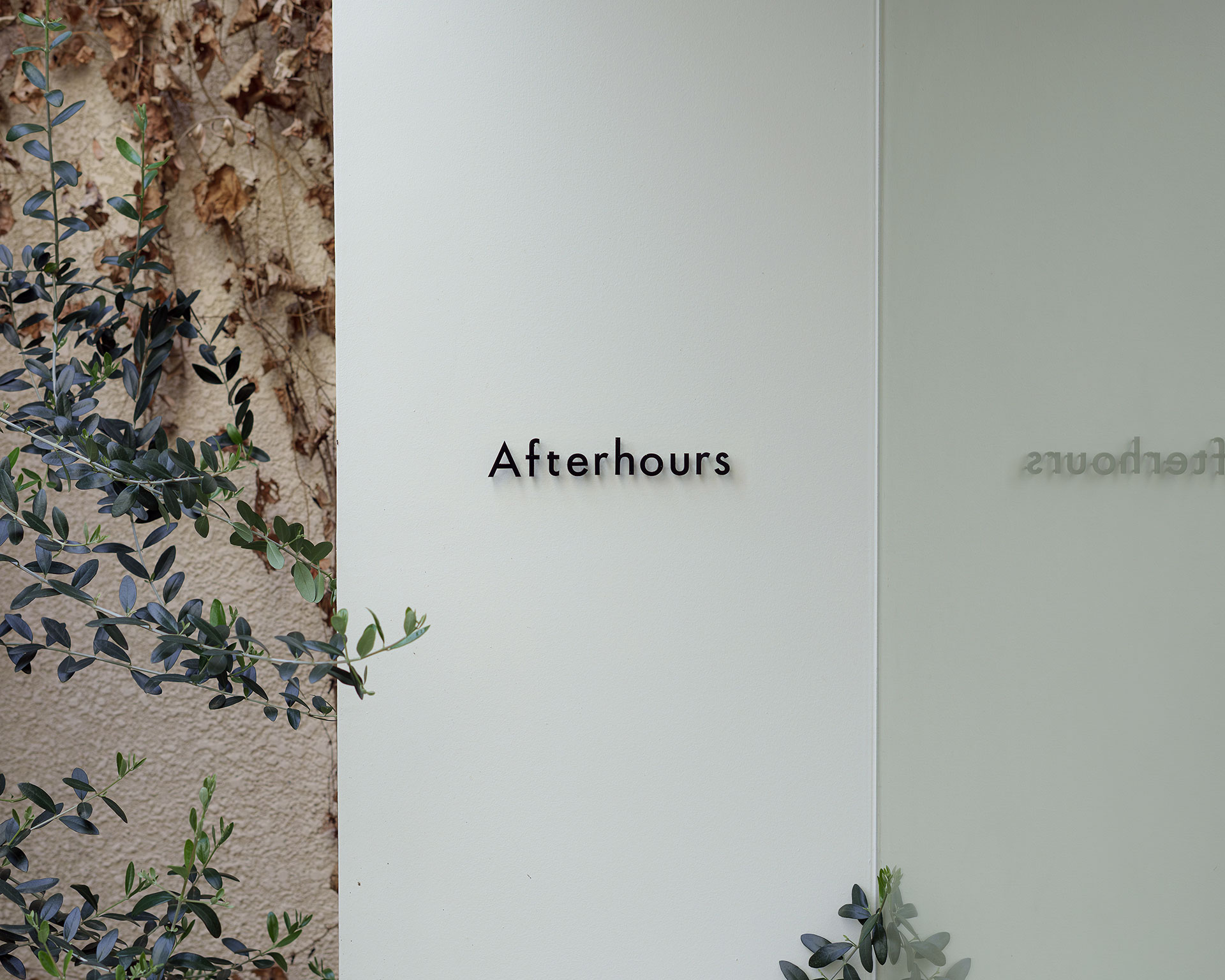 菓子店「Afterhours」の白い壁に掲げられた、シンプルで洗練された黒いロゴサイン。