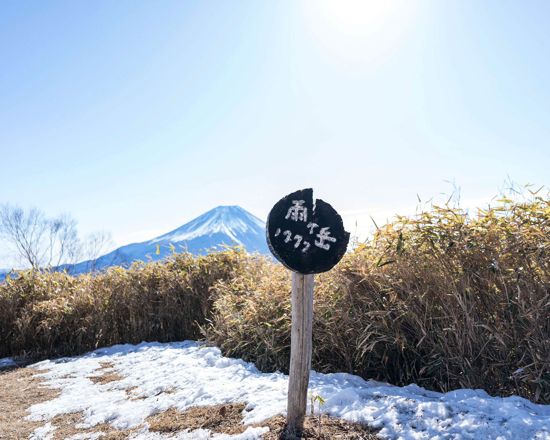 富士山を背景に、雪が残る雨ヶ岳山頂の冬の山景色