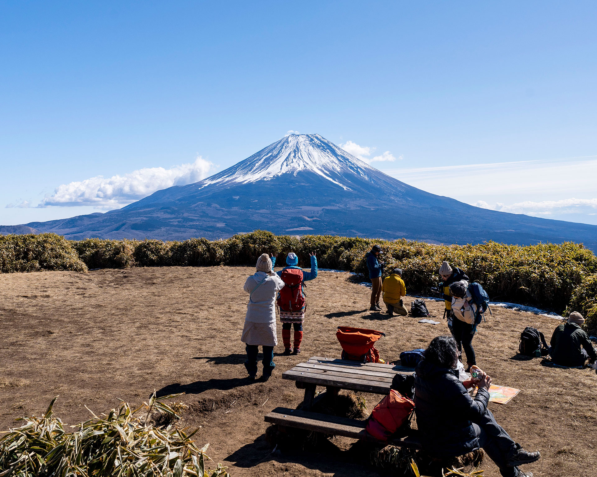 富士山を背景に竜ヶ岳山頂で休憩する登山者たち、周りには笹原が広がる