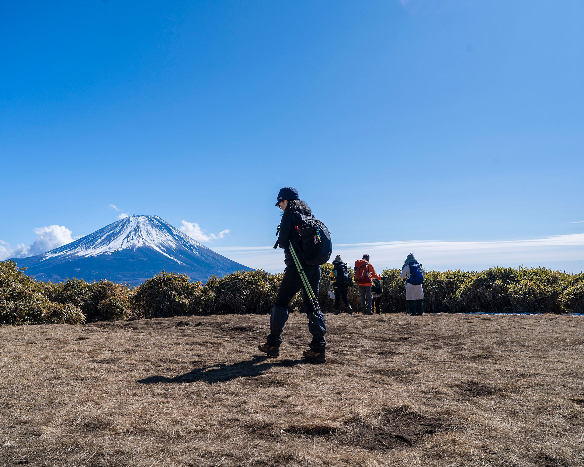 富士山を望む竜ヶ岳山頂で写真を撮る登山者たちのシルエット