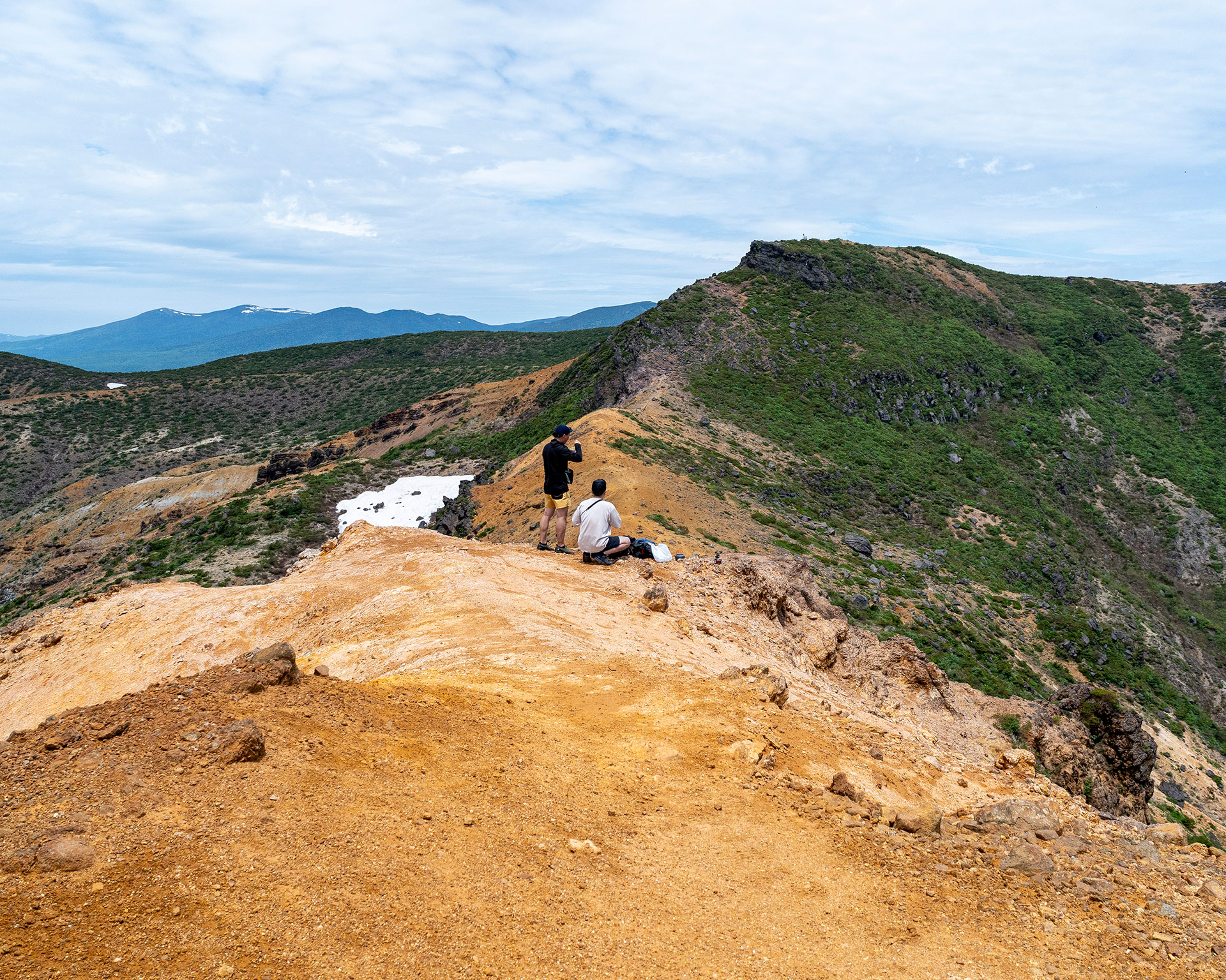 安達太良山山頂で絶景を楽しむハイカーと周辺山々のパノラマビュー