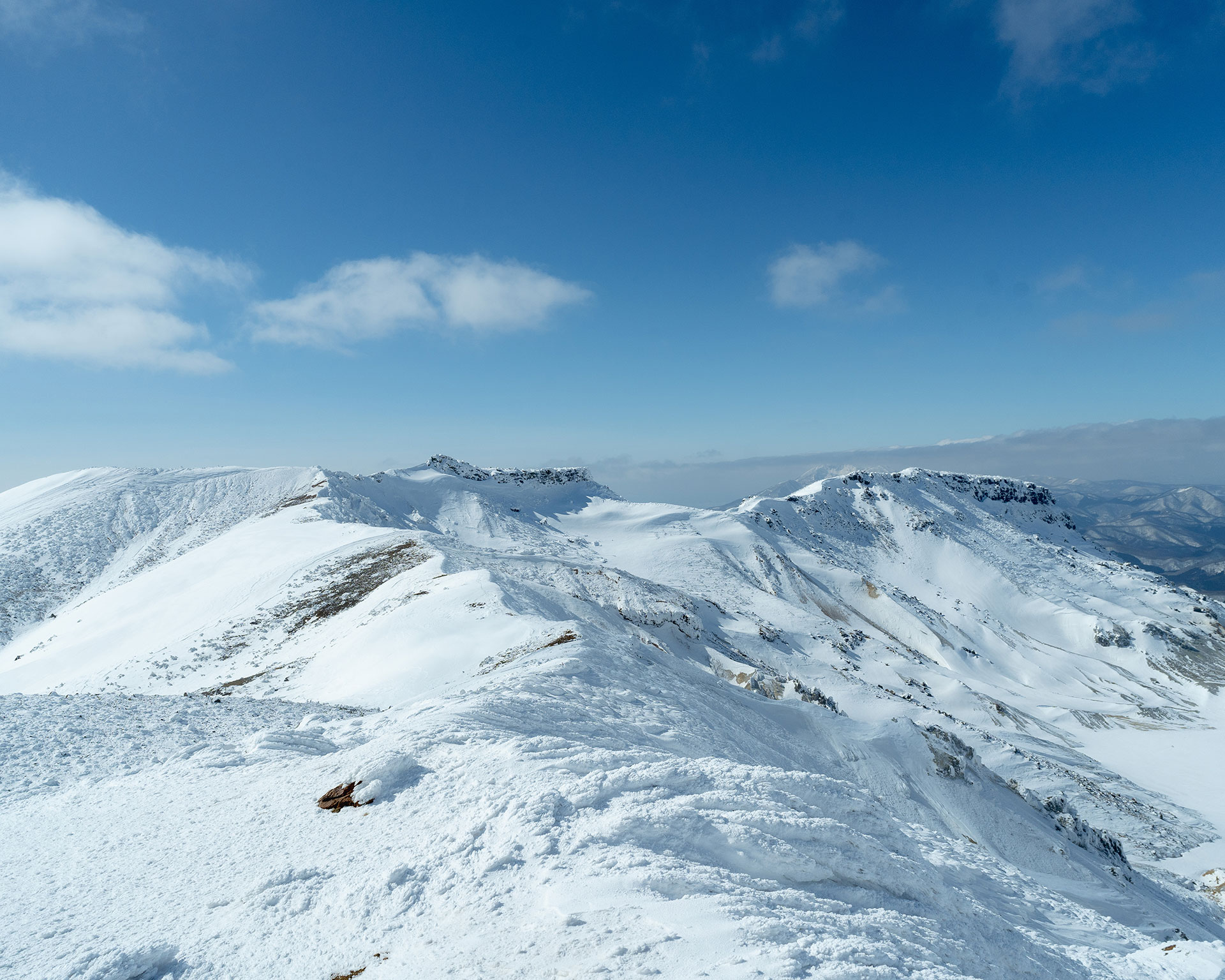 複数の雪山が連なる稜線、火口地形が見える