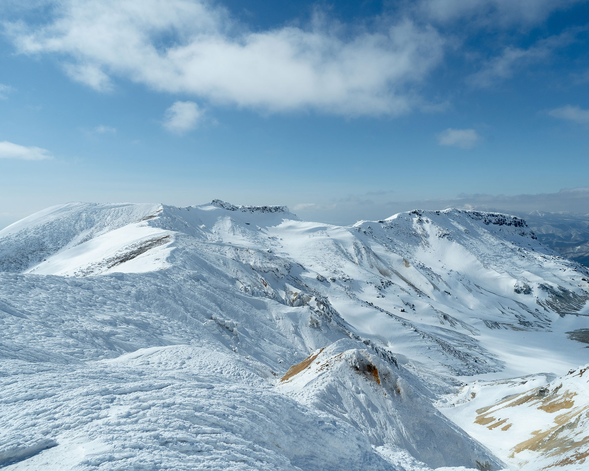 火口を囲む馬蹄形の雪山稜線、中央に平坦な火口底