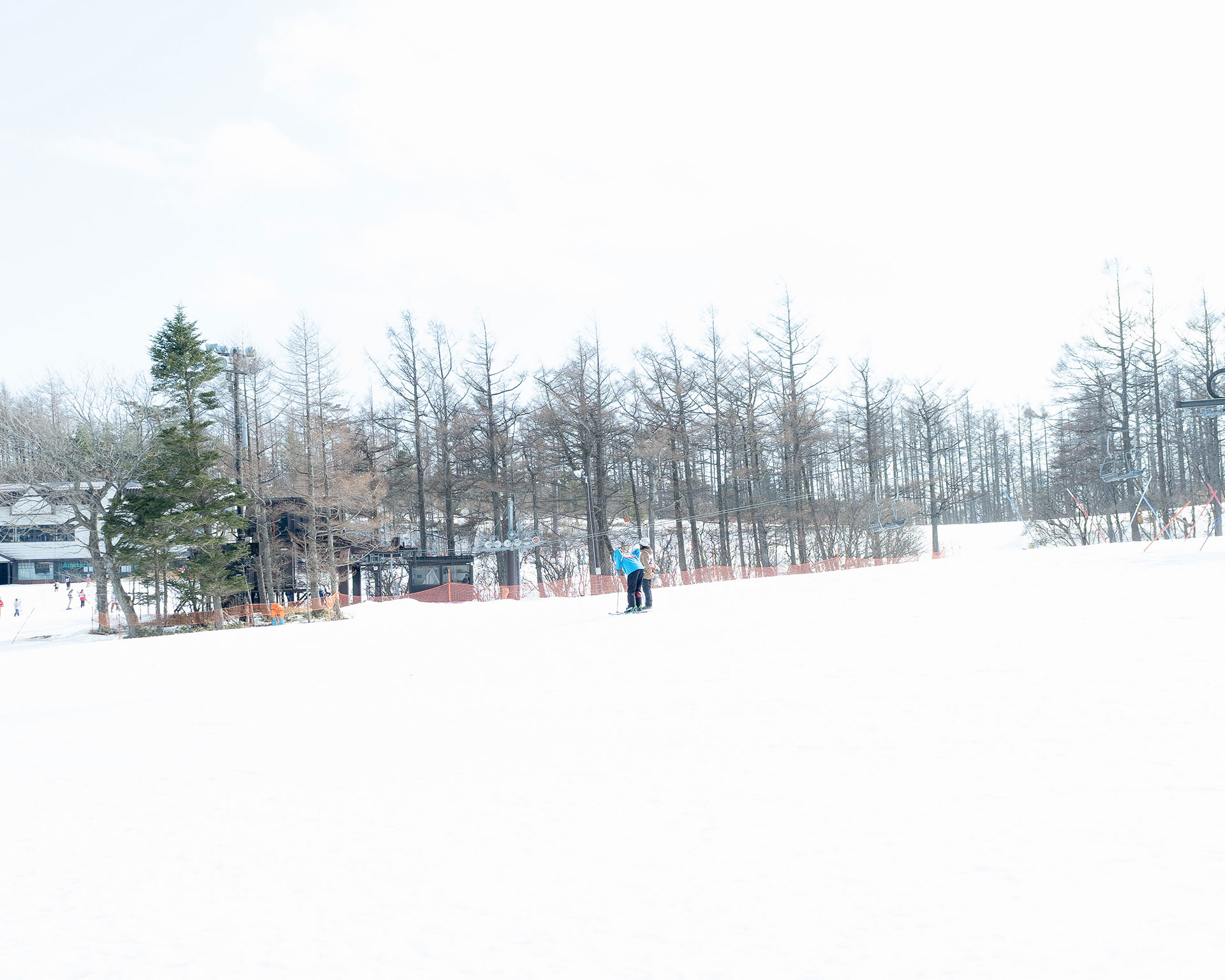 スキー場のロッジと雪原、奥に冬枯れの木々