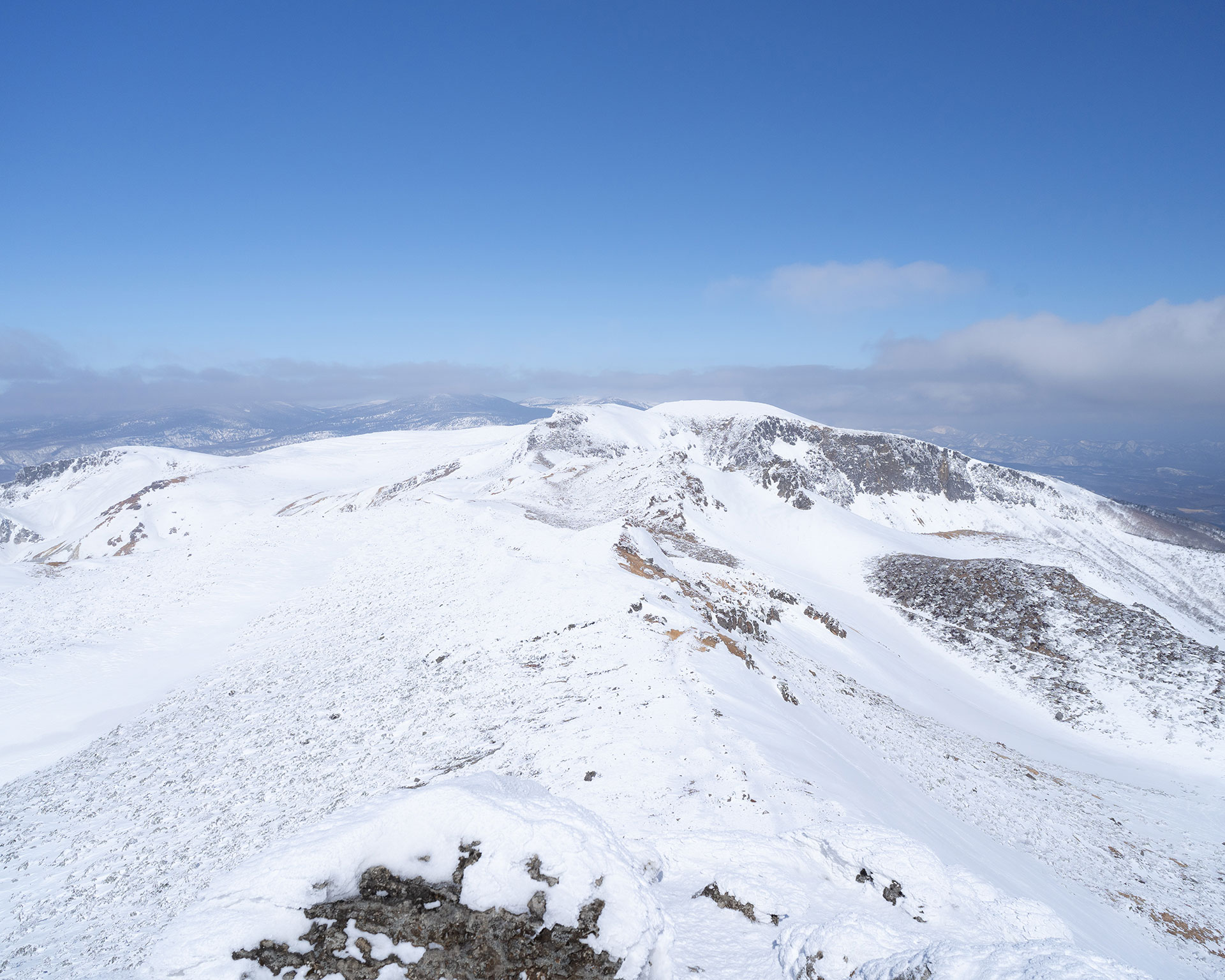 山頂から望む雪山の稜線と火口湖、雲が流れる