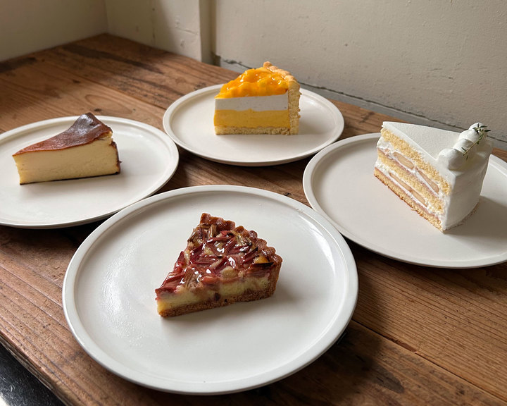 木製テーブルの上に白い皿で提供された4種類のケーキ