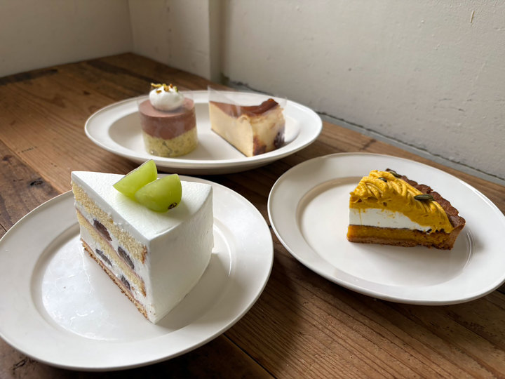 丸い形の茶色いチョコレートムースケーキ。上に白いクリームと黄色い小さな点々が飾られており、黄緑色の生地の上に置かれている。