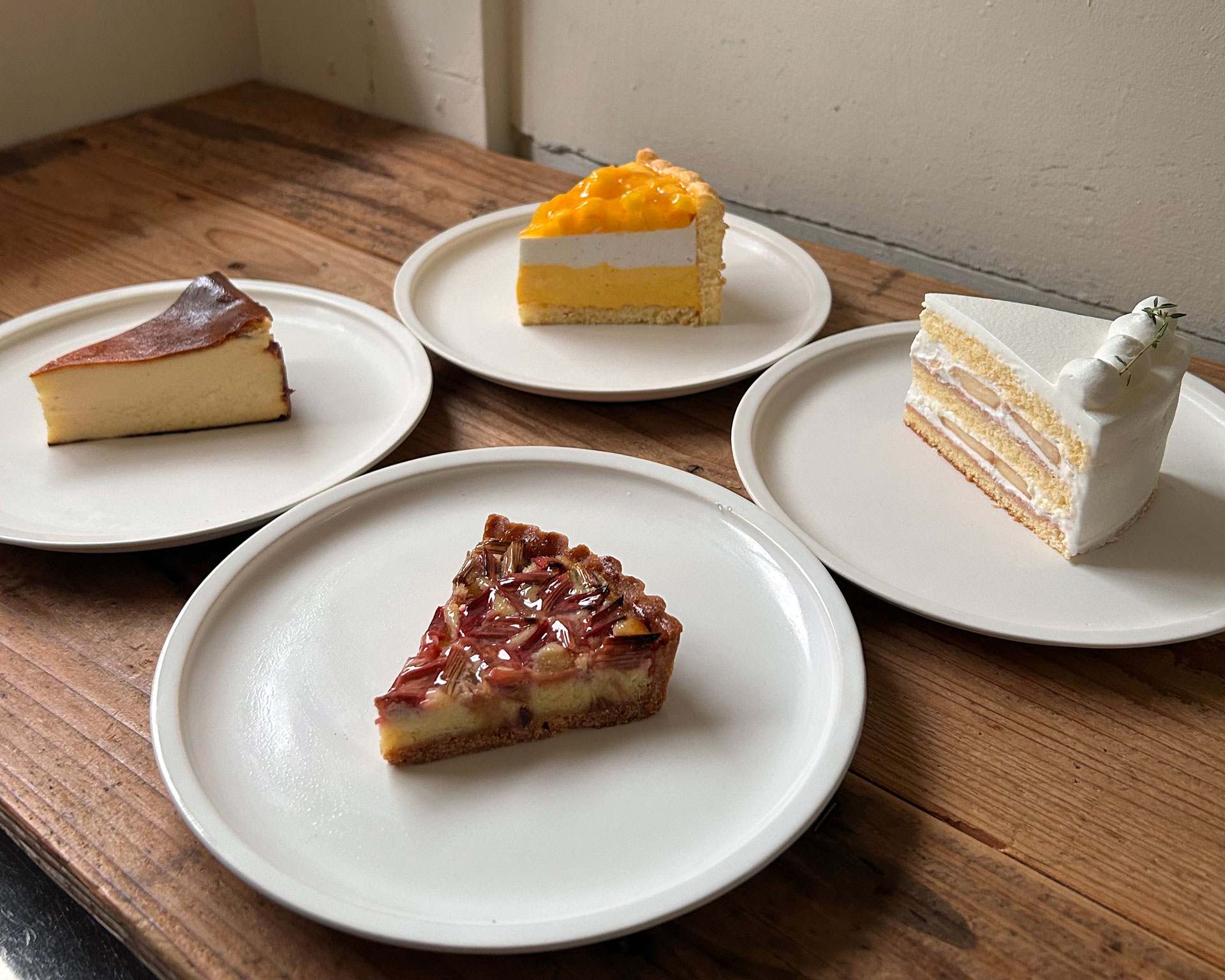 木製テーブルの上に白い皿で提供された4種類のケーキ