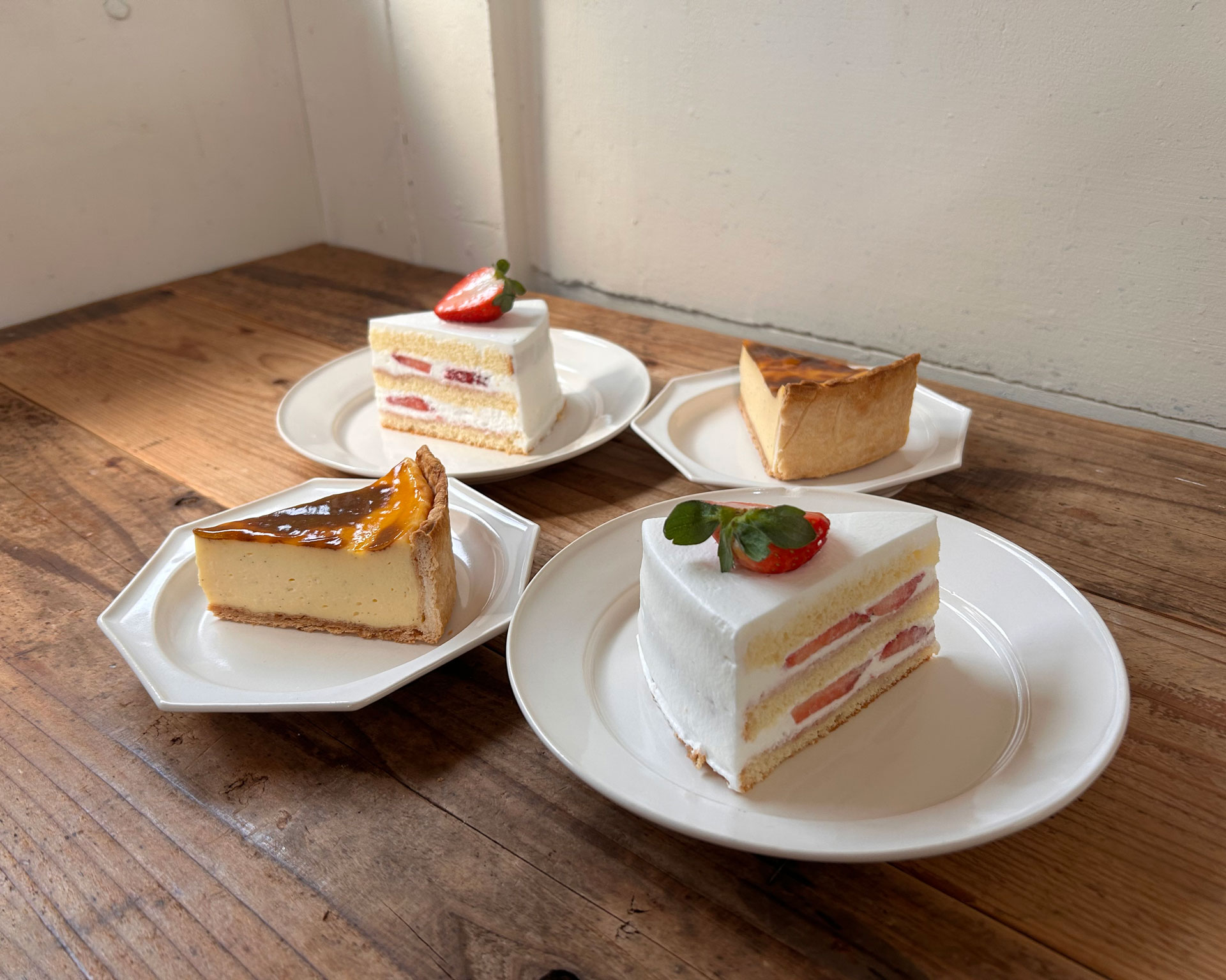木製テーブルに並べられたショートケーキとチーズケーキ