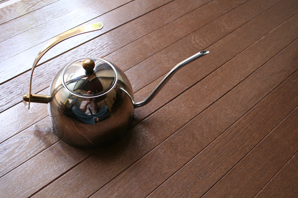 茶色の木目床に置かれたステンレス製のコーヒードリップポットカリタ「ドリップポットS600」。細長い注ぎ口とシルバーの球体が特徴的。